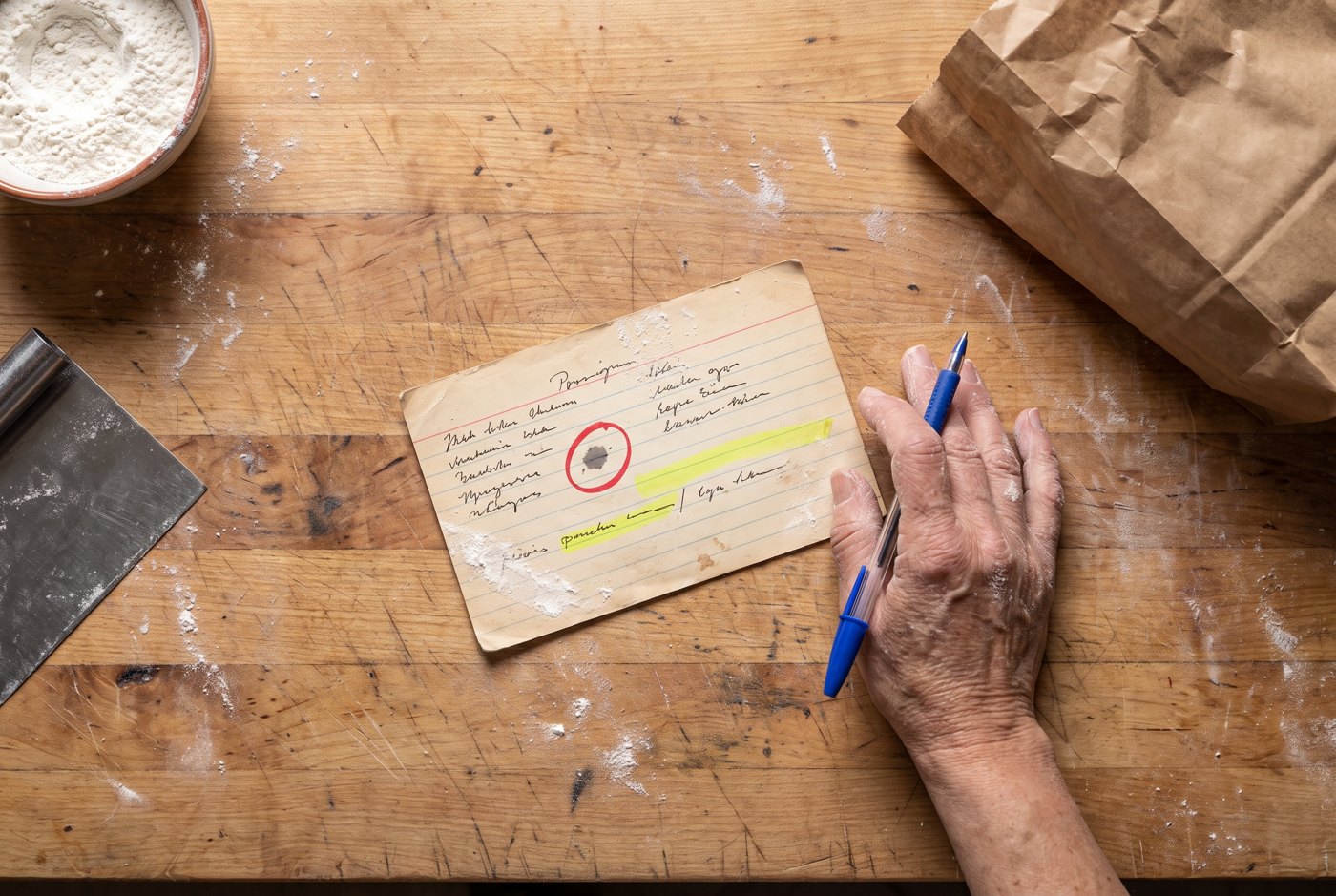 Overhead photo: a baker's hand marking up a recipe card